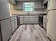 Well-lit kitchen featuring modern gray cabinets, granite countertops, stainless steel appliances, and updated laminate flooring at 13208 Massachusetts Ave, Astatula, FL 34705