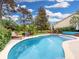 Backyard pool features patio seating, landscaping, and lush green grass under a cloudy blue sky at 14529 Falling Tree Ct, Orlando, FL 32837