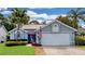 Charming single-Gathering home featuring a manicured lawn, mature palm trees, and a two-car garage with an American flag at 14529 Falling Tree Ct, Orlando, FL 32837