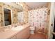 Bathroom featuring pink tile, matching sink cabinet, and shower with floral shower curtain at 1546 Royal Cir, Apopka, FL 32703