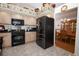 Open kitchen with black appliances, wood cabinets, and view into the dining room at 1546 Royal Cir, Apopka, FL 32703