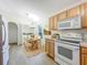 Charming eat-in kitchen boasting wood cabinets, modern appliances, and a view into the laundry area at 2353 Kingscrest Cir, Apopka, FL 32712