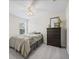 Bedroom with a dark wood dresser, mirror, ceiling fan and window, providing a calming space at 253 Fiddlewood Ct, Davenport, FL 33837