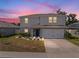 Two-story home featuring a gray exterior, two-car garage, and a manicured lawn at 253 Fiddlewood Ct, Davenport, FL 33837