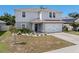 Two-story home featuring a gray exterior, two-car garage, and a manicured lawn at 253 Fiddlewood Ct, Davenport, FL 33837