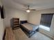 A cozy bedroom with neutral walls, carpeting, a ceiling fan, a bookcase, and a window at 3028 Lakes Crest Ave, St Cloud, FL 34772