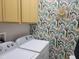 Modern laundry room with vibrant wallpaper, bright cabinetry, and efficient washer and dryer units at 3458 Sagebrush St, Harmony, FL 34773