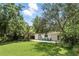 Expansive backyard featuring a well-manicured lawn, mature trees, and a stylish patio with inviting blue chairs at 509 Altaloma Ave, Orlando, FL 32803