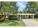Daytime shot of a charming one-story home, highlighting its lush landscaping, turquoise door, and covered carport at 509 Altaloma Ave, Orlando, FL 32803