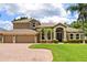 Elegant home featuring a paver driveway, three-car garage, manicured lawn, and front landscape at 748 Duff Dr, Winter Garden, FL 34787