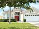 Charming single-Gathering home showcasing manicured landscaping, arched entry, and a red front door at 8023 King Palm Cir, Kissimmee, FL 34747