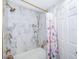 Shower with marble tile surround and gold fixtures, complete with stylish floral curtain at 1206 Culver Rd, Orlando, FL 32825