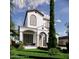 Beautiful two-story home with a covered porch, arched entrance, balcony, and lush, green landscaping at 1473 Berkshire Ave, Winter Park, FL 32789