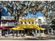 Street view of boutique storefronts featuring outdoor seating and yellow awnings beneath a large shade tree at 1473 Berkshire Ave, Winter Park, FL 32789
