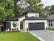 Contemporary home features a black roof, a two-car garage, and a beautifully landscaped front yard at 1526 Hempel Ave, Gotha, FL 34734