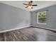 A bright, empty bedroom with a ceiling fan and a large window overlooking a fenced backyard at 1712 Riveredge Rd, Oviedo, FL 32766