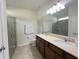 Bathroom with double vanity sinks, a walk-in shower, and neutral-colored walls at 17504 Butterfly Pea Ct, Clermont, FL 34714