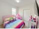 Bright bedroom with a colorful rainbow bed and a fun pink tent at 17504 Butterfly Pea Ct, Clermont, FL 34714