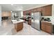Modern kitchen features stainless steel appliances, an island, brown cabinets, and tile flooring at 17504 Butterfly Pea Ct, Clermont, FL 34714