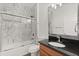 Bathroom featuring marble-look shower and wood cabinet vanity with black granite countertop at 212 Lugano Way, Debary, FL 32713