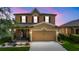 Charming two-story home with a well-manicured lawn, landscaping and a covered porch with swing at twilight at 2254 Canyon Breeze Ave, Kissimmee, FL 34746