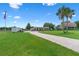 Property with a single-story house, brick-paved driveway, palm trees, and lush lawn under a clear blue sky at 2921 Lake Tohopekaliga Blvd, Kissimmee, FL 34746