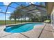 Beautiful screened-in pool area with lush green views, brick patio, and inviting lounge chairs at 2921 Lake Tohopekaliga Blvd, Kissimmee, FL 34746