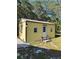 Backyard yellow shed with white trim, steps to the door, and trees at 32645 Red Oak Dr, Eustis, FL 32736
