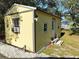 Backyard yellow shed with white trim, steps to the door, security camera and trees at 32645 Red Oak Dr, Eustis, FL 32736