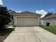 Attached two-car garage with a concrete driveway on a sunny day with white fence in view at 5118 Laval Dr, Orlando, FL 32839