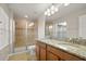 Well-lit bathroom with tiled shower, dual sinks, granite counters and wood cabinets at 5669 New Independence Pkwy, Winter Garden, FL 34787