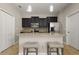 Modern kitchen featuring an island with seating, granite countertops, dark cabinets, and stainless steel appliances at 5669 New Independence Pkwy, Winter Garden, FL 34787