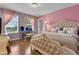 Chic bedroom with pink walls, hardwood floors, a luxurious bed, and a window for natural light at 617 Marsh Reed Dr, Winter Garden, FL 34787