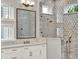 This is a bathroom with a stylish mirror, double vanity, and walk-in shower with a decorative tile accent wall at 8665 Pinter St, Orlando, FL 32827