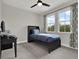 Well-lit bedroom with two windows, gray walls and carpet, with black bed frame and desk at 8665 Pinter St, Orlando, FL 32827