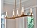 A close up of the modern chandelier with linear lights and bronze finish in the dining room at 8665 Pinter St, Orlando, FL 32827