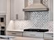 Close-up of kitchen features stylish backsplash, modern range hood, sleek countertop and cabinetry at 8665 Pinter St, Orlando, FL 32827