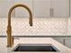 Close-up of kitchen sink with stylish faucet, countertop, backsplash and shaker cabinets at 8665 Pinter St, Orlando, FL 32827