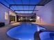 Screened pool with attached spa and travertine pavers at dusk at 8665 Pinter St, Orlando, FL 32827