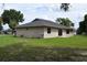 Exterior view of the home featuring a grassy lawn and mature trees at 910 Amy Ridge Ct, Kissimmee, FL 34747