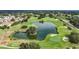 Scenic aerial view of a lush golf course featuring a tranquil pond and well-manicured greens at 9376 Se 175Th Pompion St, The Villages, FL 32162