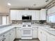 This kitchen features white cabinets, stone tile backsplash, stainless steel appliances, and light countertops at 9376 Se 175Th Pompion St, The Villages, FL 32162