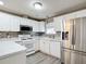 Well-lit kitchen with stainless steel refrigerator, plentiful white cabinetry, stainless microwave, and patterned backsplash at 9376 Se 175Th Pompion St, The Villages, FL 32162
