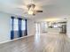 Open-concept living room boasts wood floors, ceiling fan, and flows seamlessly into the kitchen area at 9376 Se 175Th Pompion St, The Villages, FL 32162