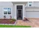 Close-up of front door showcasing tidy landscaping, brick entryway and gray exterior, enhancing curb appeal at 944 Benjamin Trl, Davenport, FL 33837