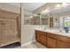 Bathroom featuring double sinks, wood cabinets, and a tiled shower with glass door at 9440 Myrtle Creek Ln # 1003, Orlando, FL 32832