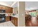 Traditional kitchen with brown cabinets, black appliances, and view to living room with sliding glass doors at 9440 Myrtle Creek Ln # 1003, Orlando, FL 32832