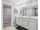 Bathroom with double sinks, white cabinetry, and walk-in closet at 10009 Randal Walk St, Orlando, FL 32832
