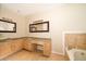 Bright bathroom featuring double sinks with granite counters, and a soaking tub with tiled surround at 13524 Lake Luntz Dr, Winter Garden, FL 34787
