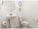 Bright half-bathroom with a pedestal sink, round mirror, decorative wall accents and white toilet at 13556 Abberwick Dr, Orlando, FL 32832